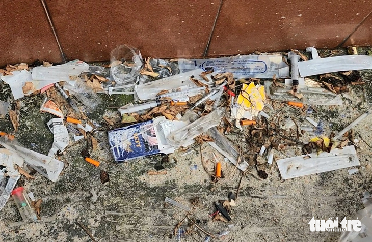 Used needles and syringes are left next to a tomb in the Binh Hung Hoa Cemetery. Photo: Ngoc Khai / Tuoi Tre
