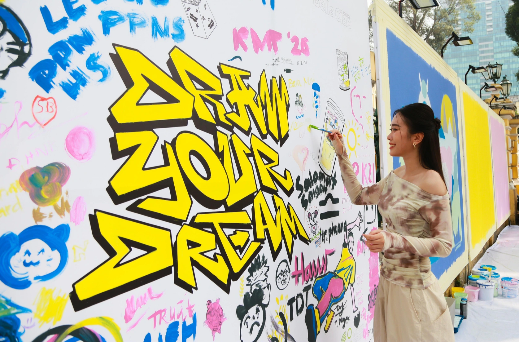 Miss Peace Vietnam 2022 Tran Thi Ban Mai contributes to a collaborative painting at the Saigon Urban Street Fest in front of the Saigon Central Post Office in District 1, Ho Chi Minh City, December 8, 2023. Photo: Supplied
