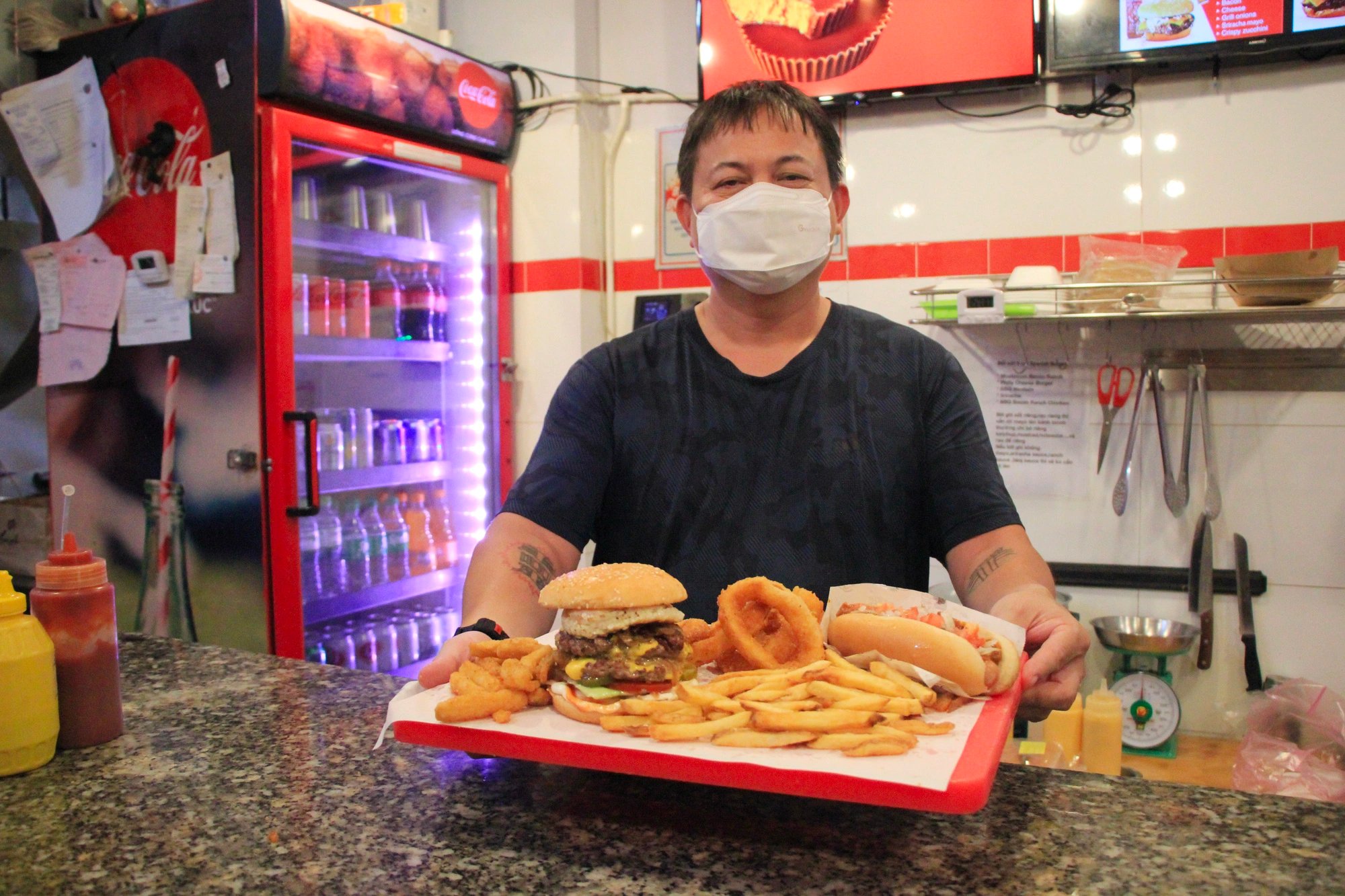 Charlie Ta serves burger and side dishes to a diner at Chuck's Burger in Binh Thanh District, Ho Chi Minh City. Photo: Dong Nguyen / Tuoi Tre News