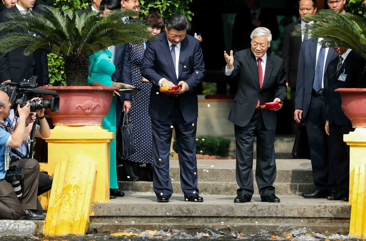 Vietnam’s Party chief Nguyen Phu Trong (R) and Chinese Party General Secretary and President Xi Jinping feed fish in the fish pond situated at the late President Ho Chi Minh relic site in November 2017. Photo: Nguyen Khanh / Tuoi Tre