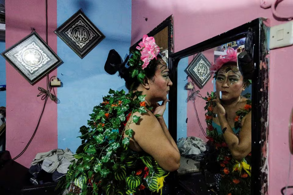 Nuke Herawati, 43, a trans woman who wears a recycled material dress to bring awareness to LGBT rights and environmental protection, looks in the mirror before a Trans Super Heroes fashion show at a traditional market in Jakarta, Indonesia, December 17, 2023. Photo: Reuters