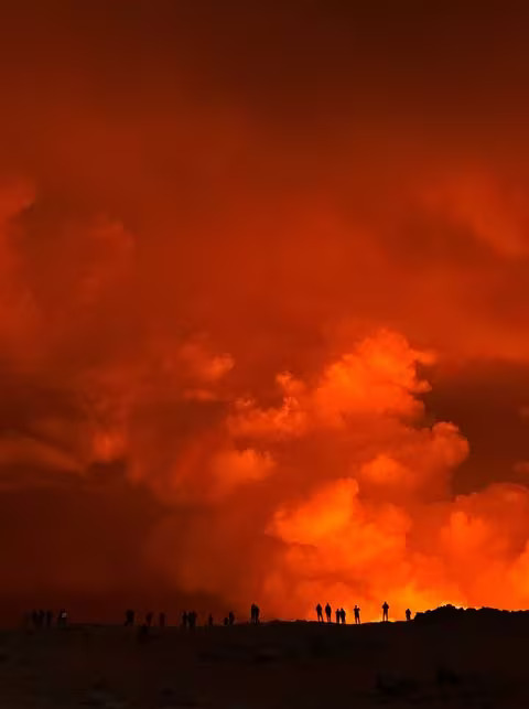 People are silhouetted against the glow from a volcano's eruption, in this view from Keflavik, Iceland December 18, 2023 in this picture obtained from social media. Photo: Reuters