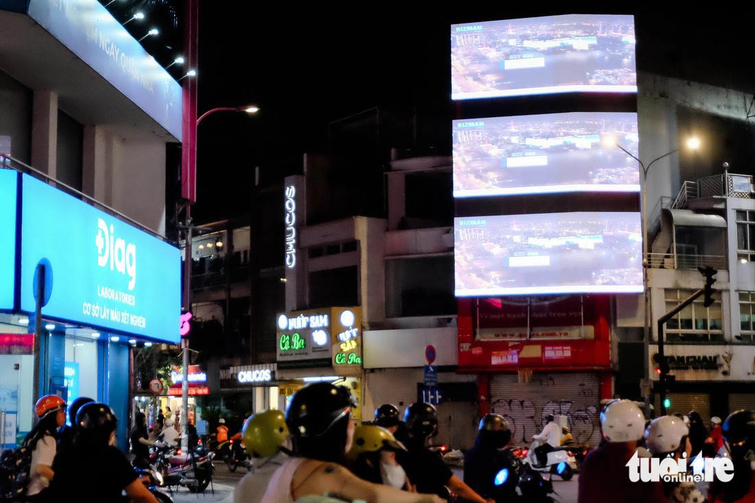 Three LED screens on the façade of a high-rise building at the intersection of Dinh Tien Hoang and Dien Bien Phu Streets in District 1, Ho Chi Minh City.
