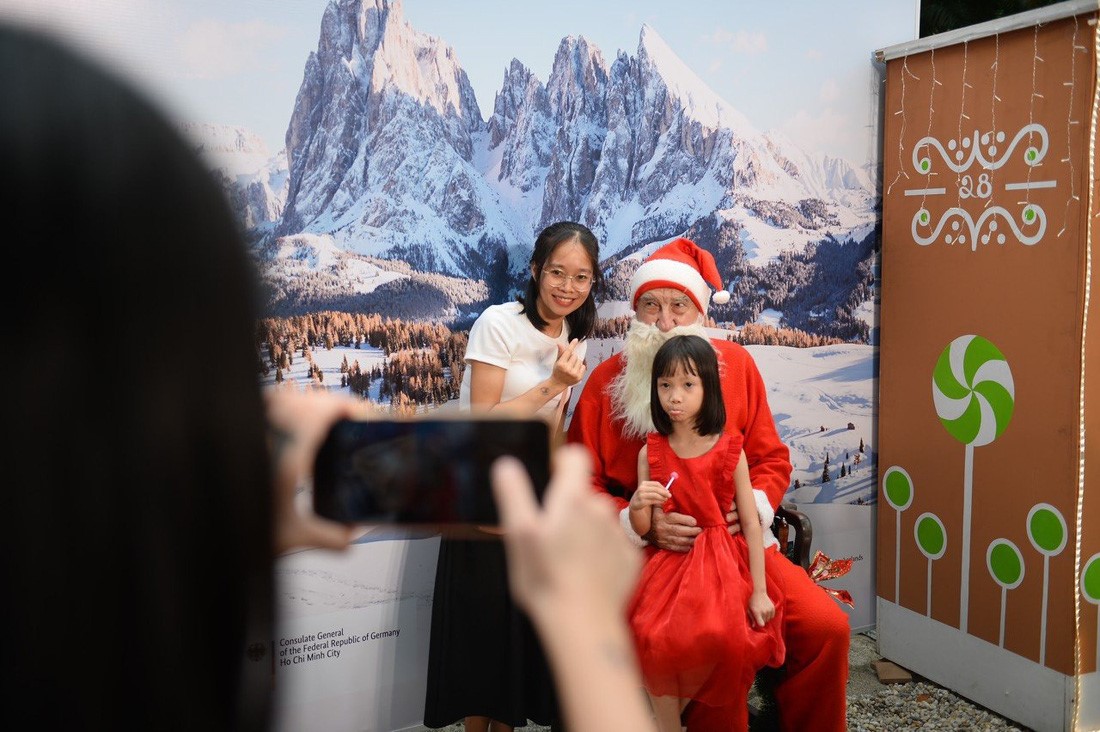 A woman and a child pose for a photo with a French man dressed in a Santa Claus costume. Photo: Hai Quynh / Tuoi Tre
