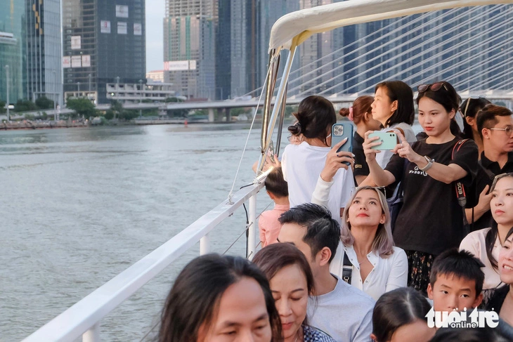 Passengers on an open-top double-decker boat floating down the Saigon River photograph the entire city at sunset and take selfies. Photo: Phuong Nhi / Tuoi Tre
