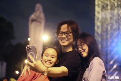 A Ho Chi Minh City resident takes a selfie of his family in front of the statue of Our Lady of Peace at the Notre Dame Cathedral in District 1, Ho Chi Minh City, southern Vietnam, on December 24, 2023. Photo: Phuong Quyen / Tuoi Tre