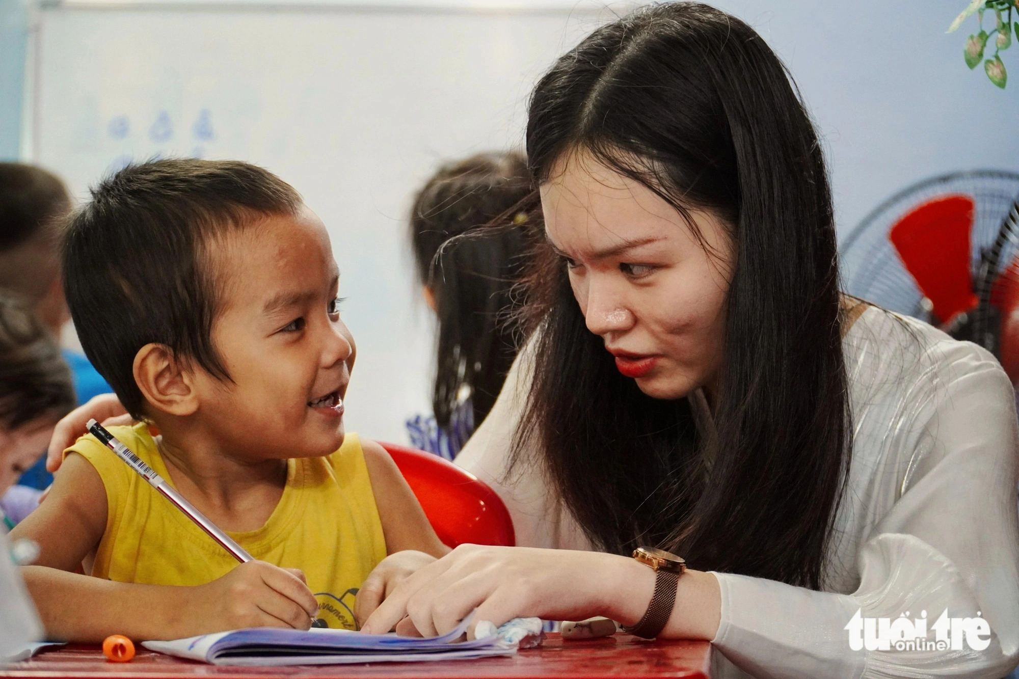 A teaching volunteer helps a kindergartener learn the alphabet. Photo: Tran Hoai / Tuoi Tre