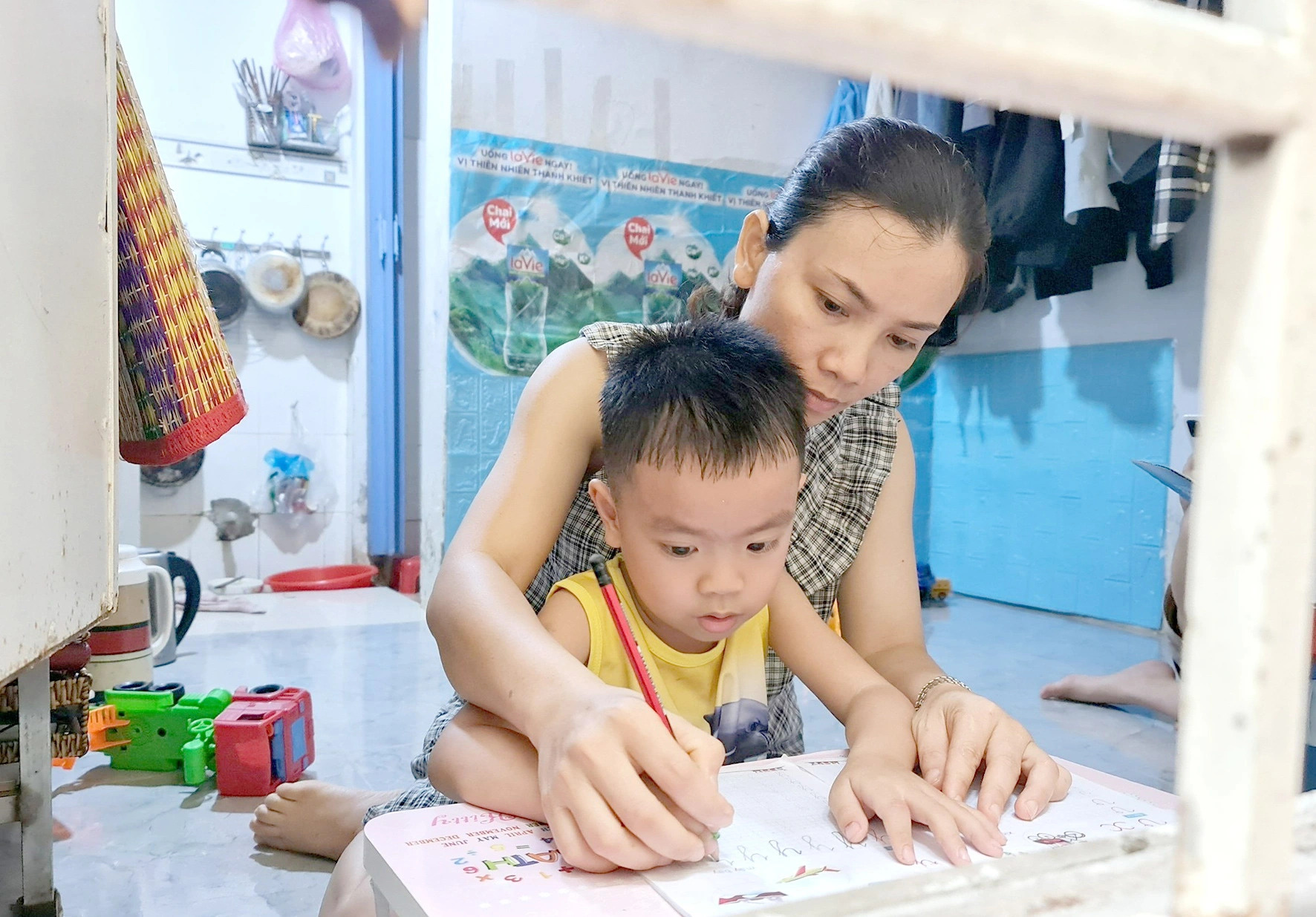 A female worker helps her child in learning instead of going to work, as her company reduced working hours due to a shortfall of orders. Photo: C.Trieu / Tuoi Tre