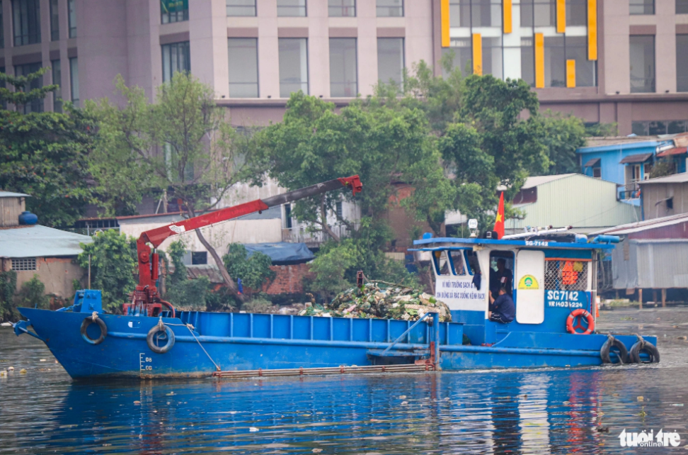 Environmental protection employees use a boat to fish garbage out of Doi Canal in District 8, Ho Chi Minh City. Photo: Chau Tuan / Tuoi Tre