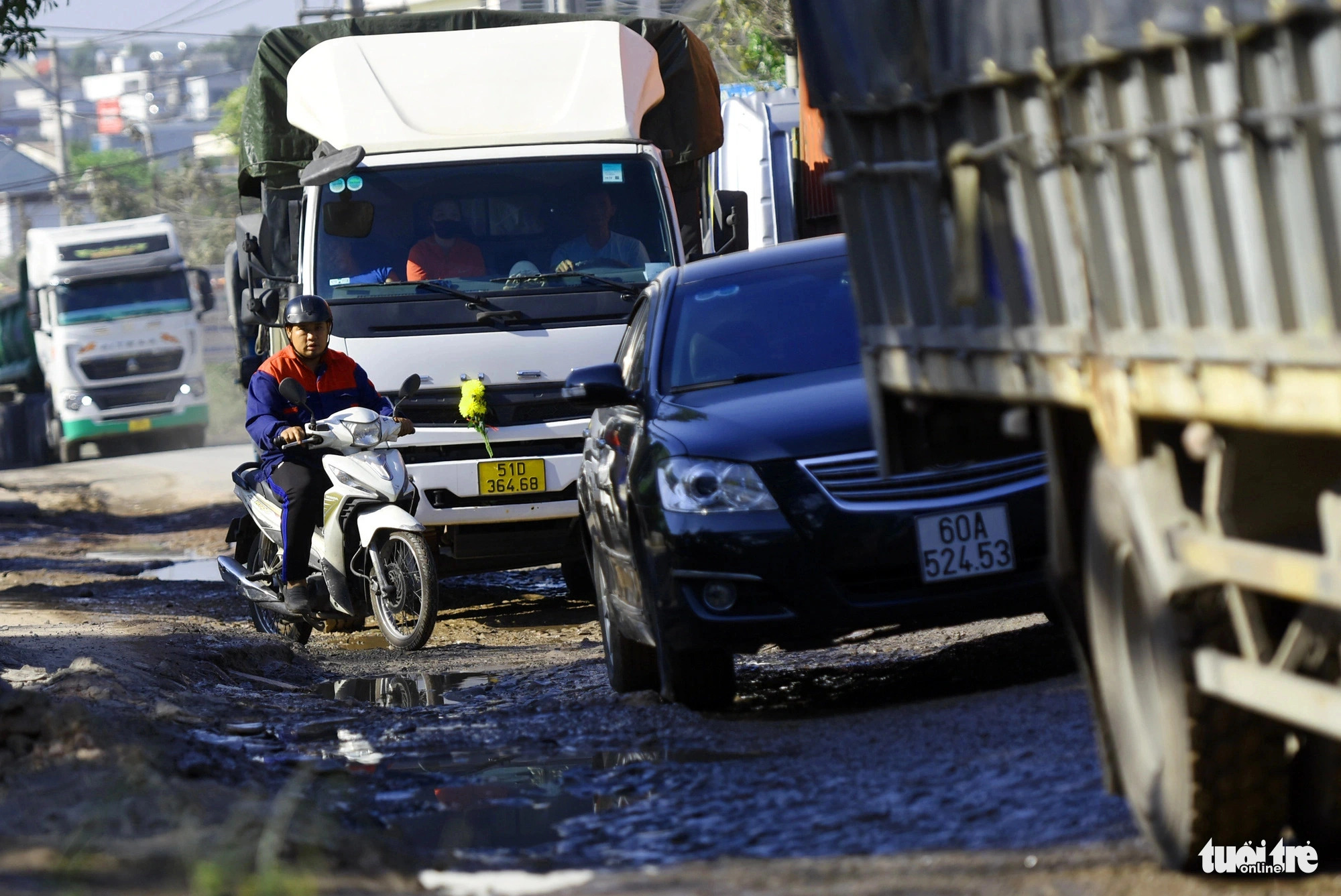 The road is just wide enough for two cars to travel parallel to each other at the same time, forcing motorcyclists to drive near bigger vehicles to avoid hitting potholes. Photo: A. Loc / Tuoi Tre