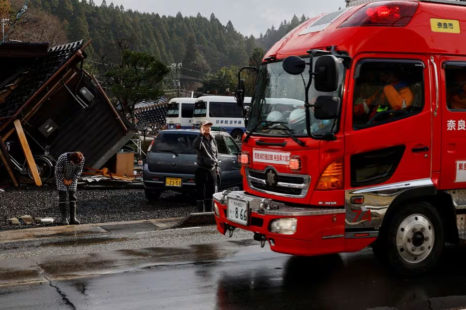 Yutaka Obayashi and his wife Akiko, who live in their car after the earthquake, greet firefighters in gratitude, in Wajima, Ishikawa Prefecture, Japan, January 6, 2024. Photo: Reuters