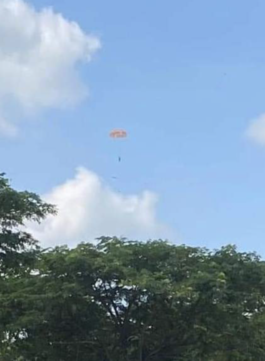 A still image taken from a video clip shows the pilot of a falling military plane jumping off it with a parachute