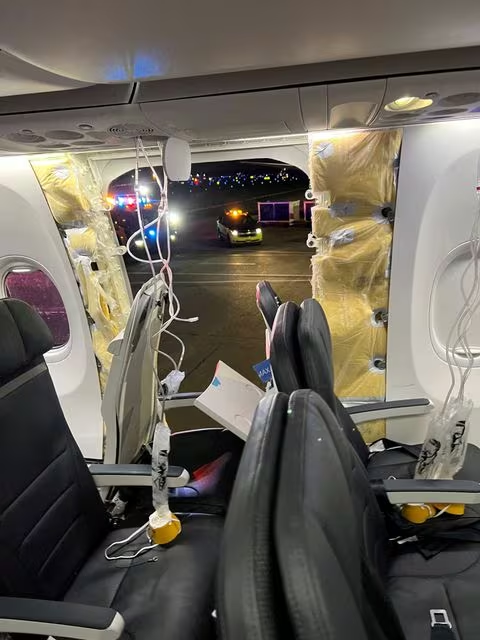 Passenger oxygen masks hang from the roof next to a missing window and a portion of a side wall of an Alaska Airlines Flight 1282, which had been bound for Ontario, California and suffered depressurization soon after departing, in Portland, Oregon, U.S., January 5, 2024 in this picture obtained from social media. Instagram/@strawberrvy via Reuters