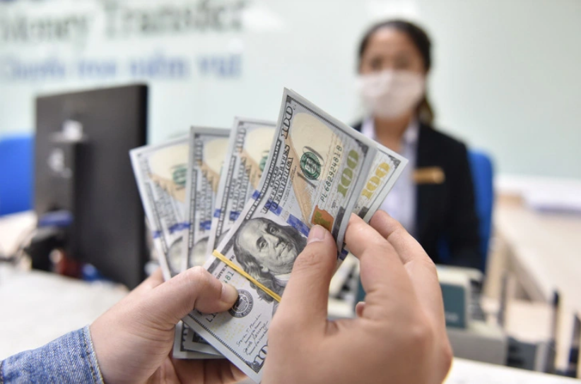 A customer holds stacks of U.S. banknotes at a bank on Nguyen Thi Minh Khai Street in Ho Chi Minh City. Photo: Ngoc Phuong / Tuoi Tre