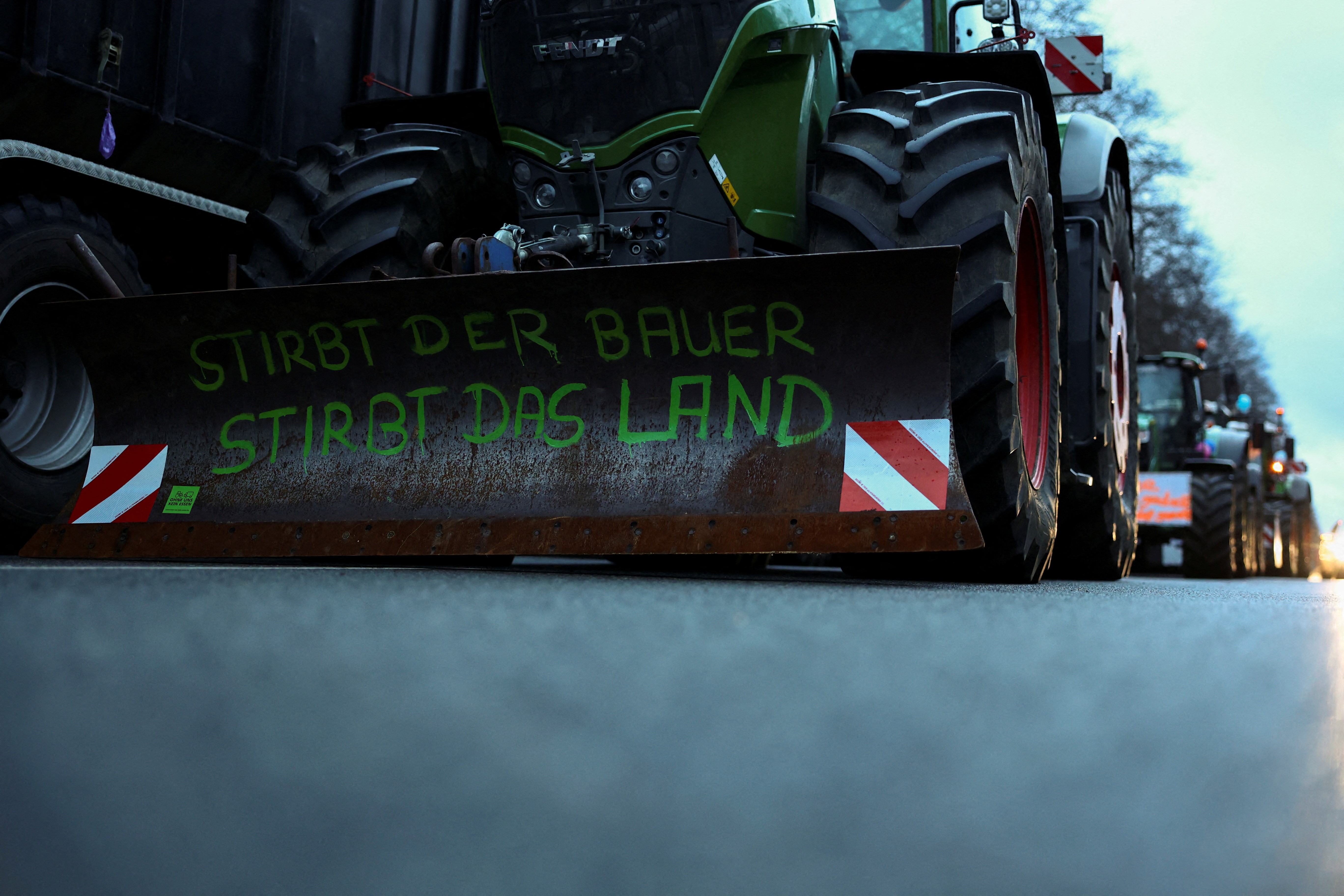 Tractors drive at the Strasse des 17. Juni in front of the Brandenburg Gate to prepare one day before a large protest against the cut of farm vehicle tax subsidies of the so-called German Ampel coalition government, in Berlin, Germany, January 14, 2024. A writing reads: 'If the farmer dies, the country dies'. Photo: Reuters