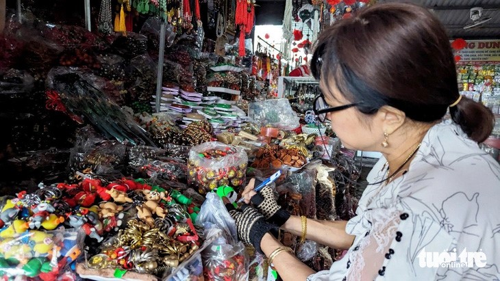 A trader at Dong Ba Market in Thua Thien-Hue Province sticks price tags on her keychain and souvenir products. Photo: Nhat Linh / Tuoi Tre