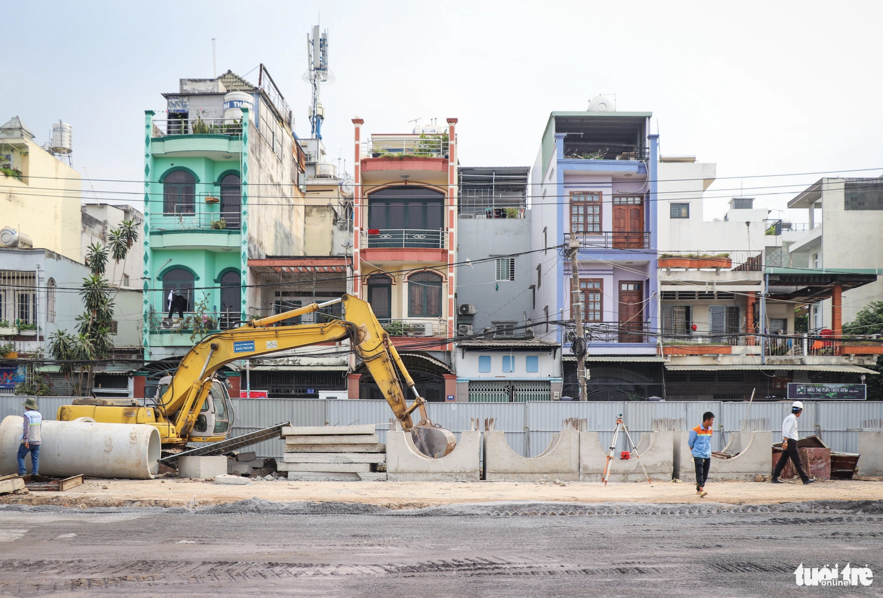 Construction workers inside the iron fence are busy building a road aimed at easing traffic jams facing the Tan Son Nhat International Airport area. Photo: Chau Tuan / Tuoi Tre