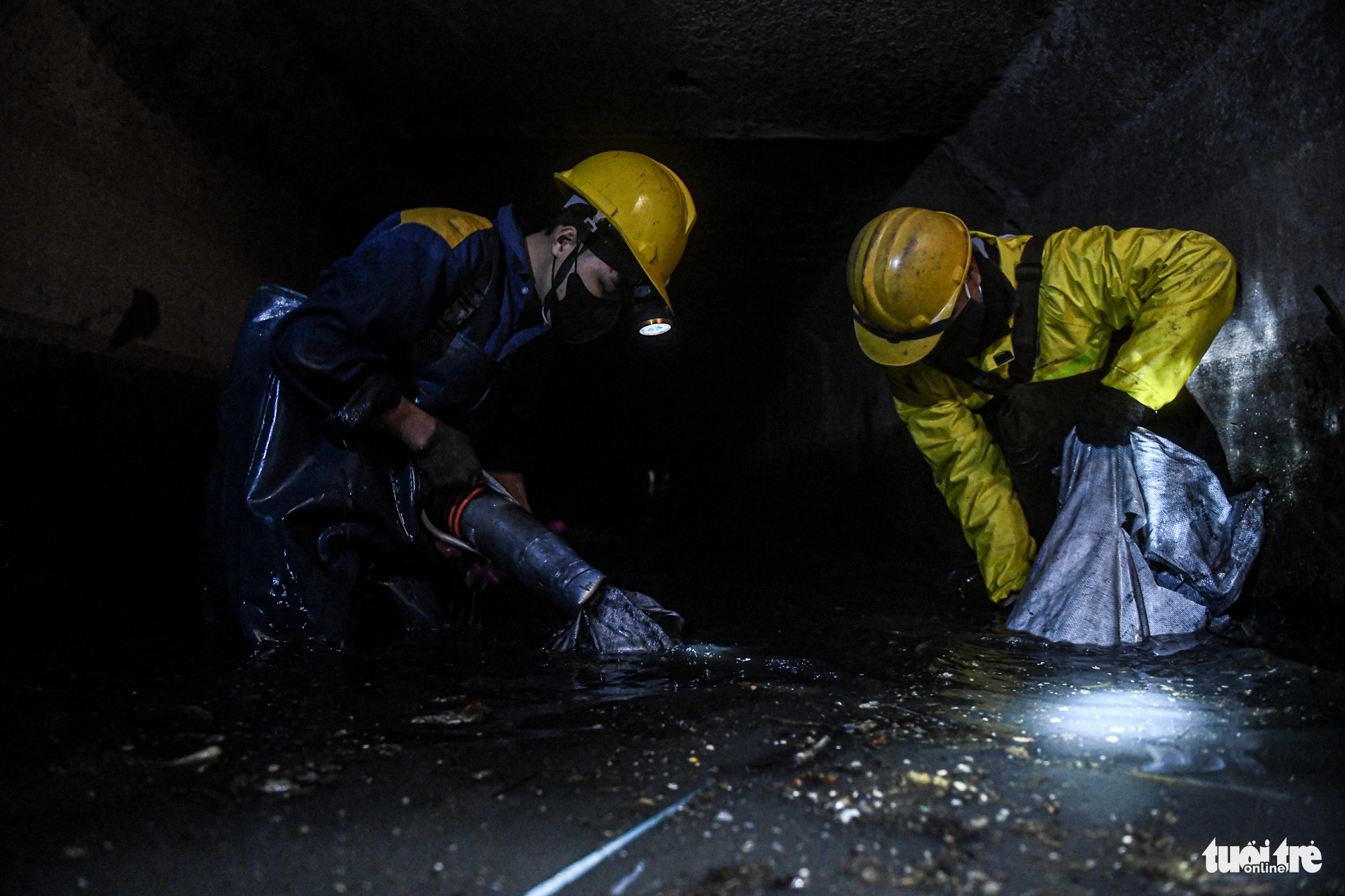 Sewer workers brave cold weather down a sewer in the Yen So area of Hoang Mai District, Hanoi, January 25, 2024. Photo: Nam Tran / Tuoi Tre