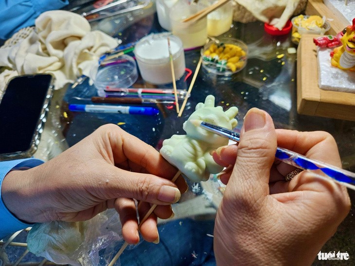 An artisan paints a small dragon model. Photo: Minh Chien / Tuoi Tre