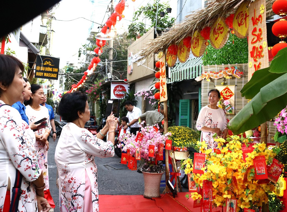 Women donning ‘ao dai’ (Vietnam's traditional long gown) pose for photos with Tet decorations. Photo: Be Hieu / Tuoi Tre