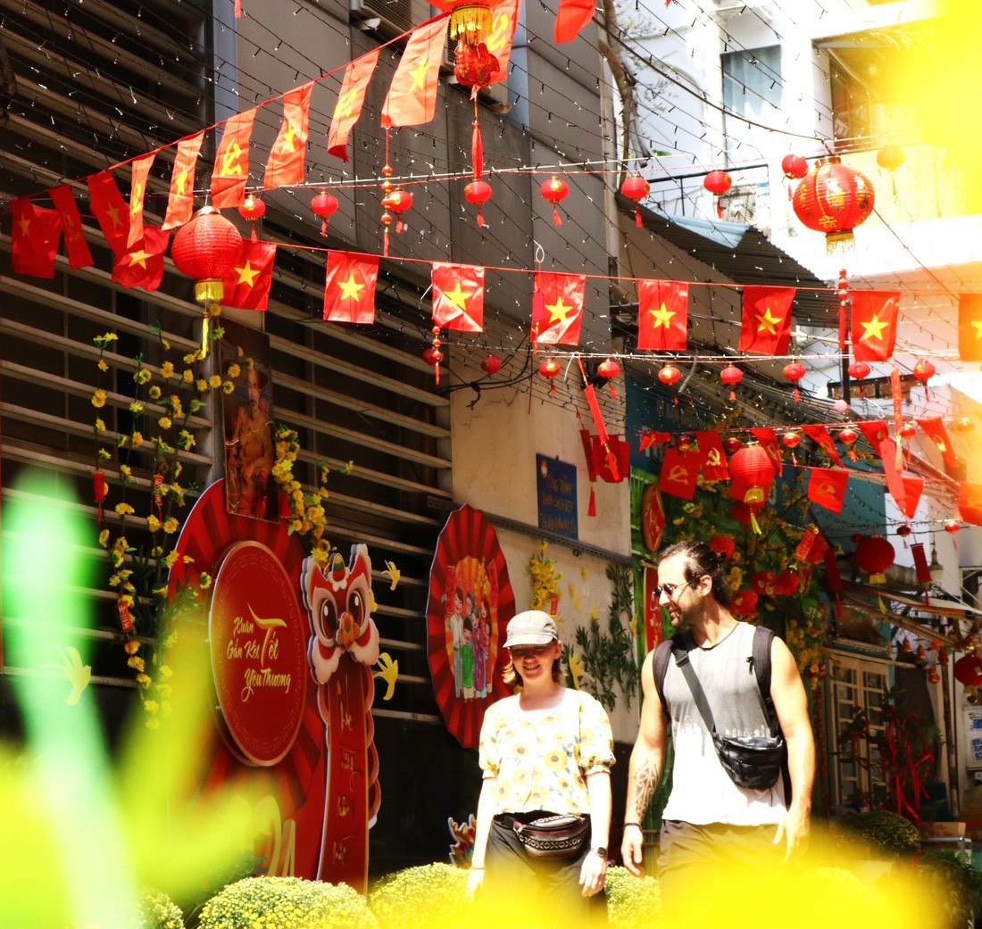 Two foreigners take a walk in an alley donning Tet-themed decorations in Ho Chi Minh City. Photo: Be Hieu / Tuoi Tre