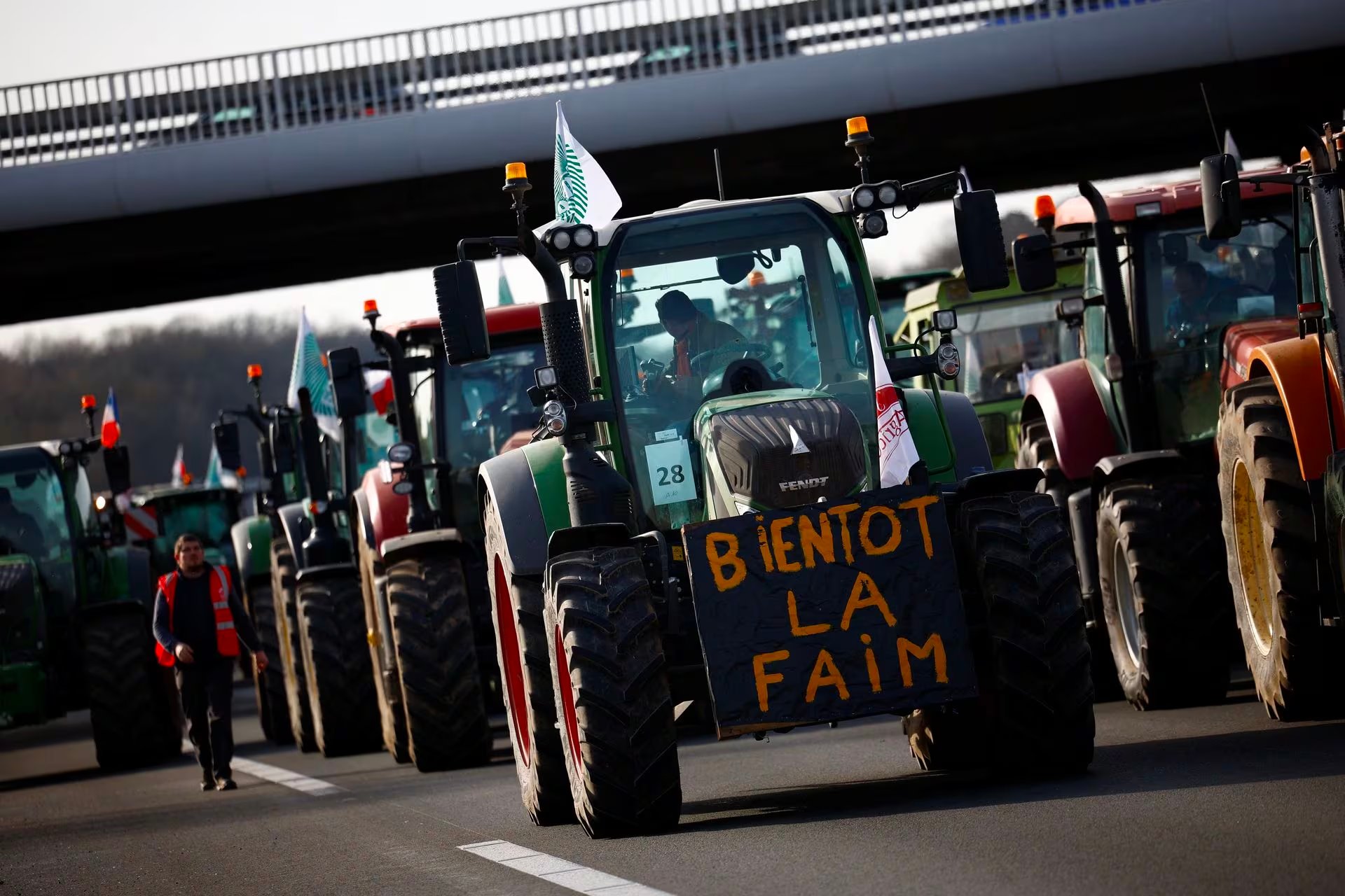 French farmers drive their tractors on a highway as they protest over price pressures, taxes and green regulation, grievances shared by farmers across Europe, in Longvilliers, near Paris, France, January 29. The placard reads 'Soon hunger.'