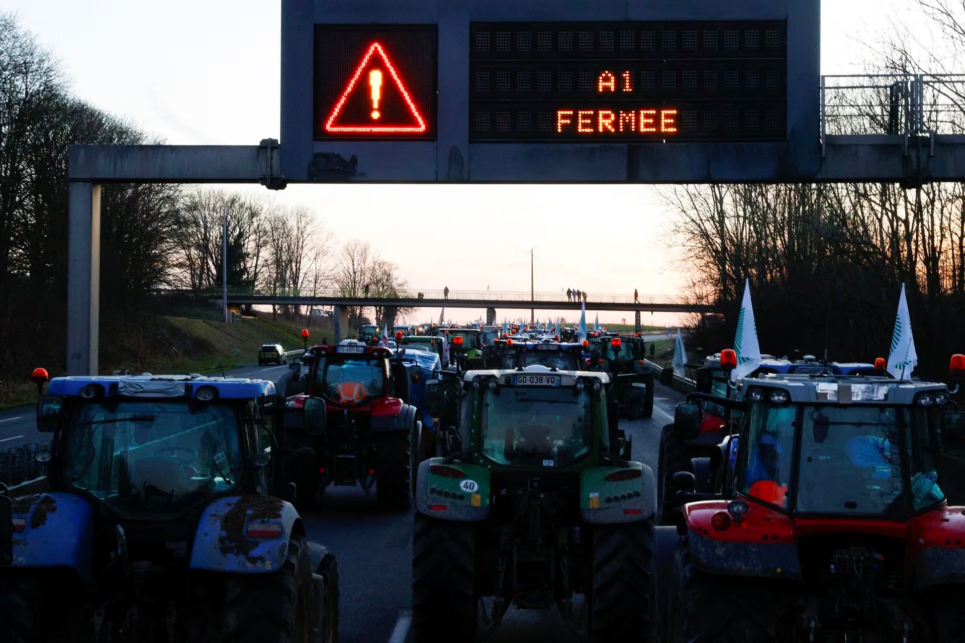 A sign displays a message as tractors block a highway during a French farmers' protest over price pressures, taxes and green regulation, grievances shared by farmers across Europe, in Chamant, near Paris, France, January 26. Sign reads: 'A1 closed'. Photo: Reuters