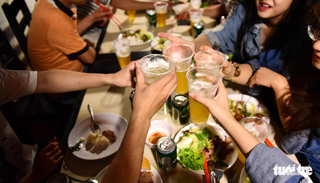 Drinkers clink their glasses of beer at a restaurant in Ho Chi Minh City. Photo: Quang Dinh / Tuoi Tre