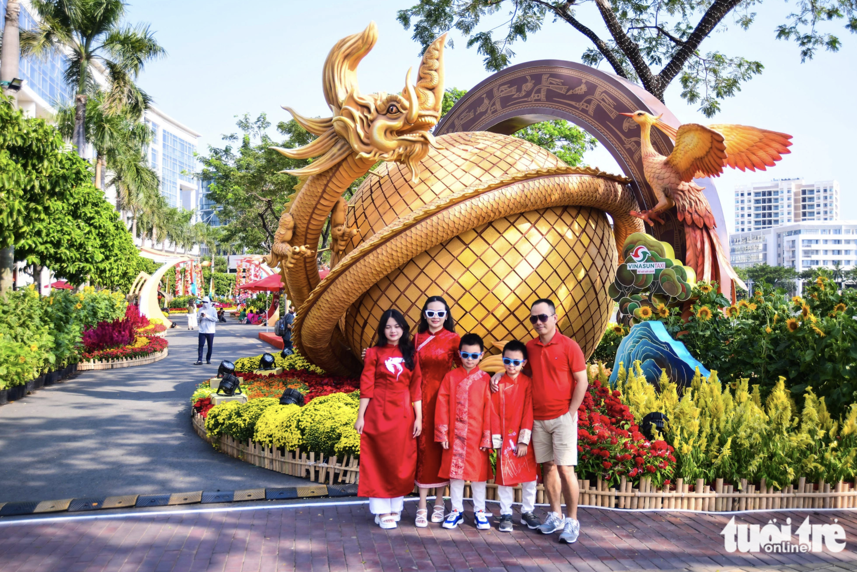 A family of five wear red ao dai to take photos with a miniature on Phu My Hung Flower Street, which opened to the public in Ho Chi Minh City on February 3, 2024. Photo: Quang Dinh / Tuoi Tre