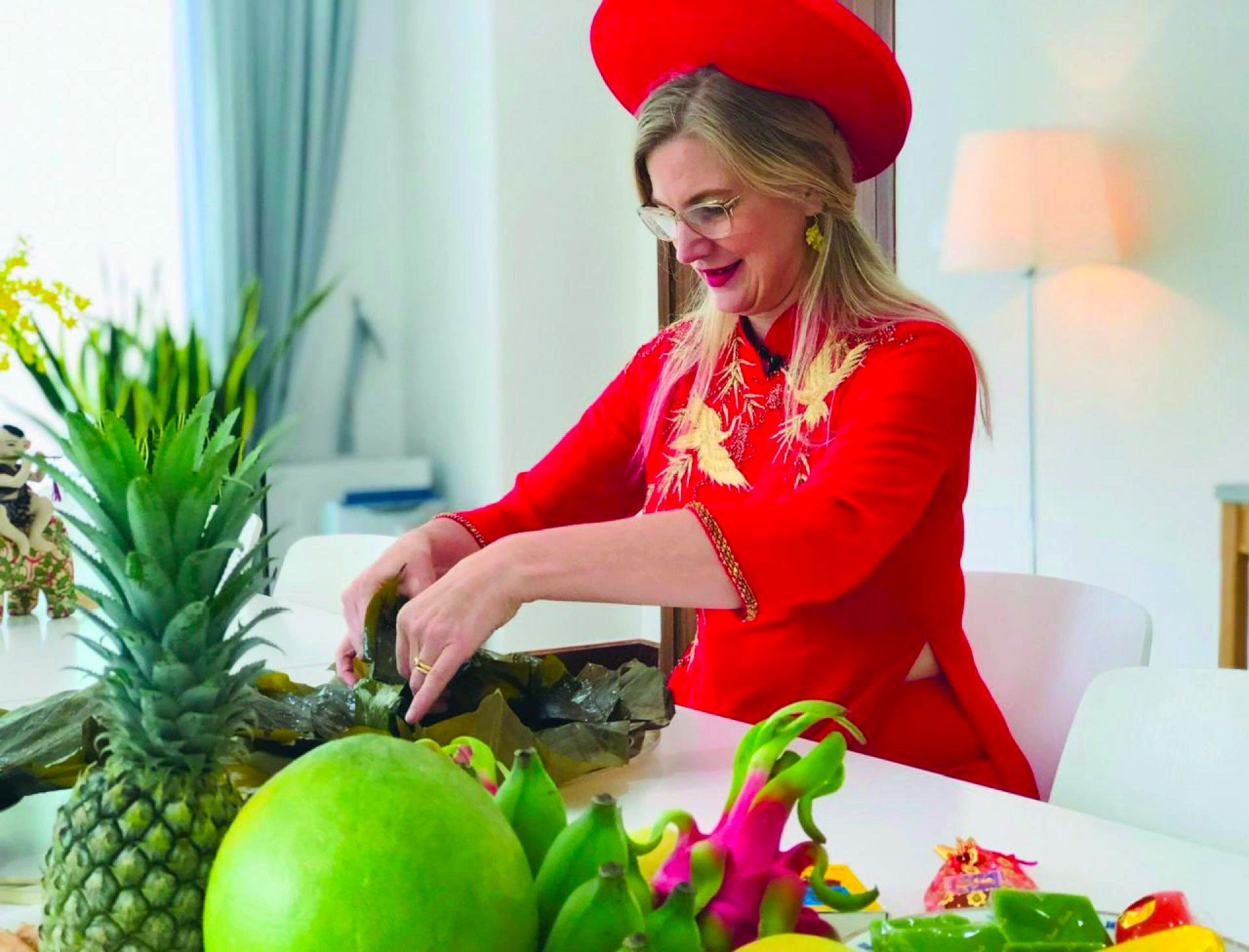 In this photo, Swedish Ambassador to Vietnam Ann Måwe wears 'áo dài' (Vietnamese traditional costume) and Vietnamese traditional turban 'khăn đóng' while opening a loaf of banh chung (Vietnamese traditional Tet food in the northern region).