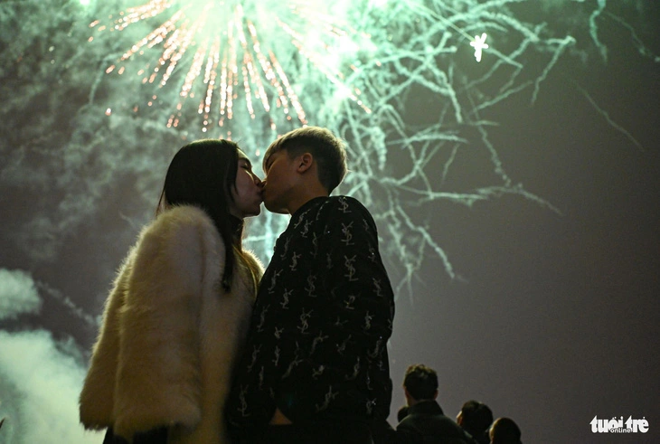 Under the night sky lit up by a drone light show, a couple of youths share a kiss in celebration of the Lunar New Year in Hanoi, February 9, 2024. Photo: Hong Quang / Tuoi Tre