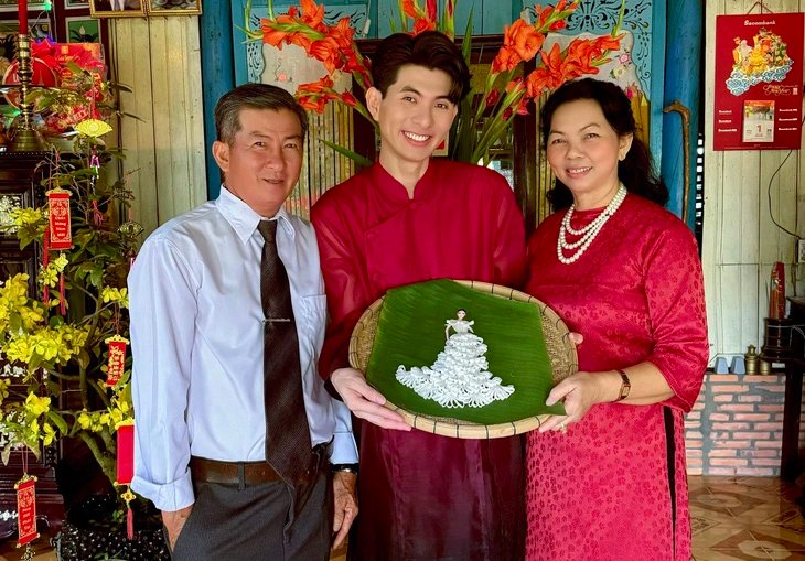 Nguyen Minh Cong (centered) holds his 'mứt dừa hoa' dress design ad poses for a photo with his parents during the 2024 Tet holiday. Photo: Supplied