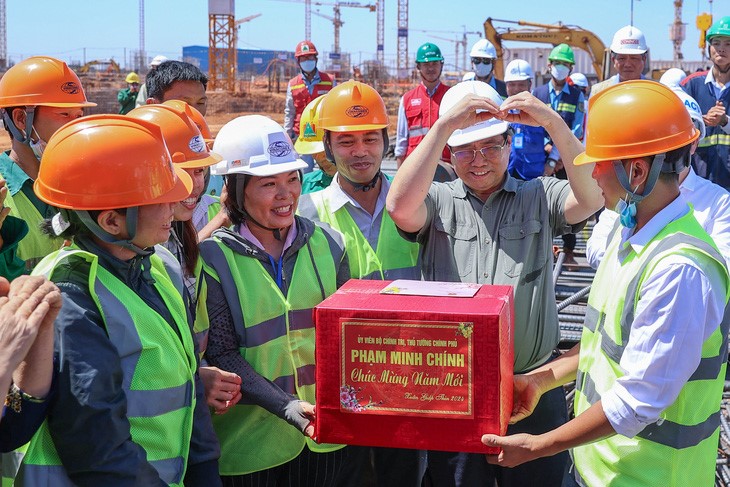 Prime Minister Pham Minh Chinh (R, 2nd) gives a Tet gift to workers at the construction site of the Long Thanh International Airport project in Dong Nai Province.