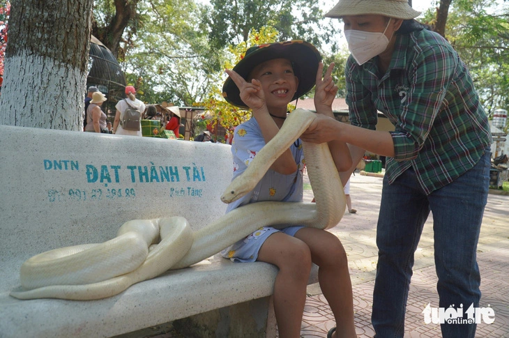 Visitors enjoy posing for a photo with a python at Dong Tam Snake Farm in Tien Giang Province, situated in Vietnam’s Mekong Delta region, during the 2024 Tet (Lunar New Year) holiday.