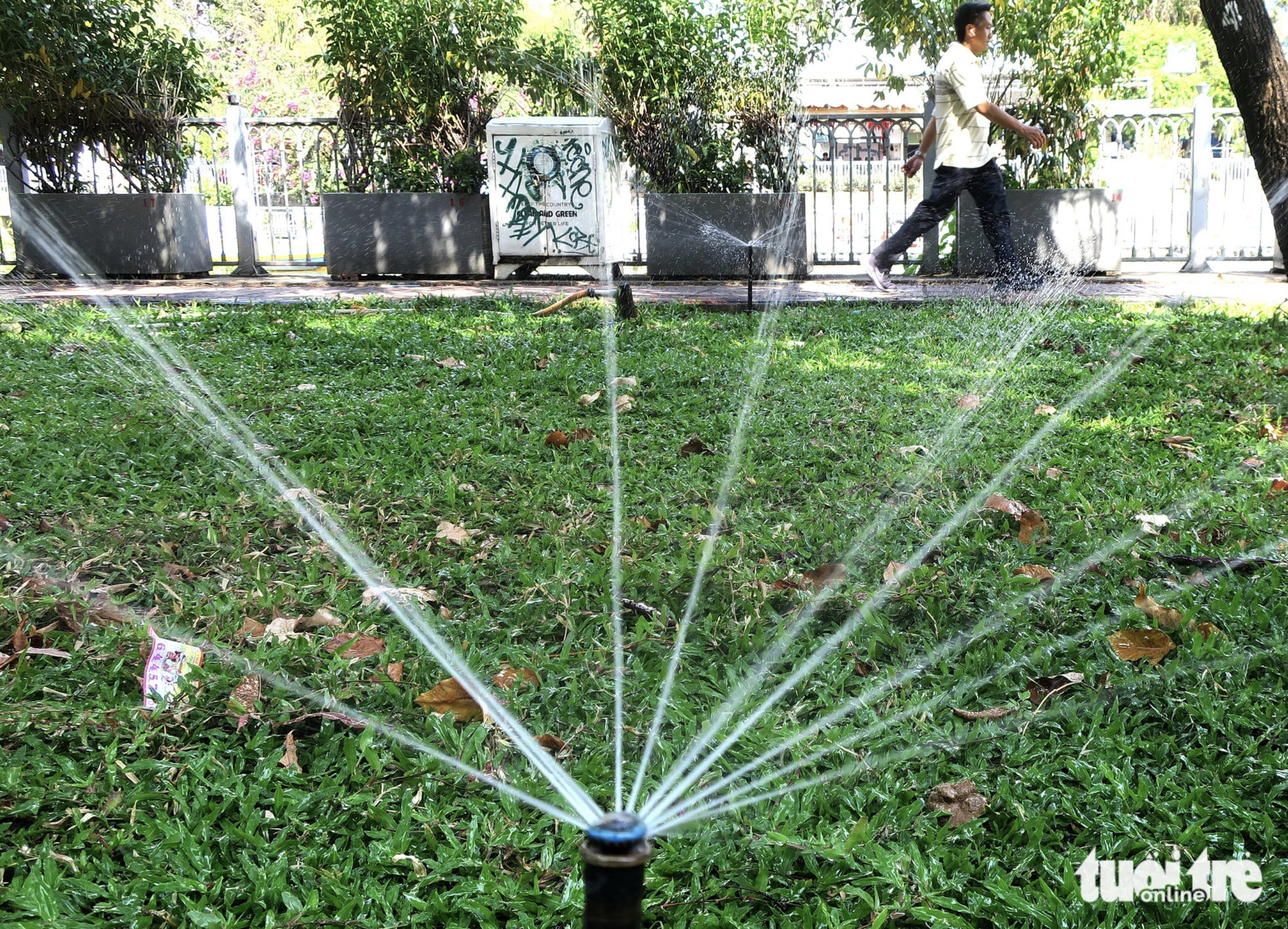 A man walks past sprinklers at a park in Ho Chi Minh City on a hot day in February 2024. Photo: T.T.D. / Tuoi Tre