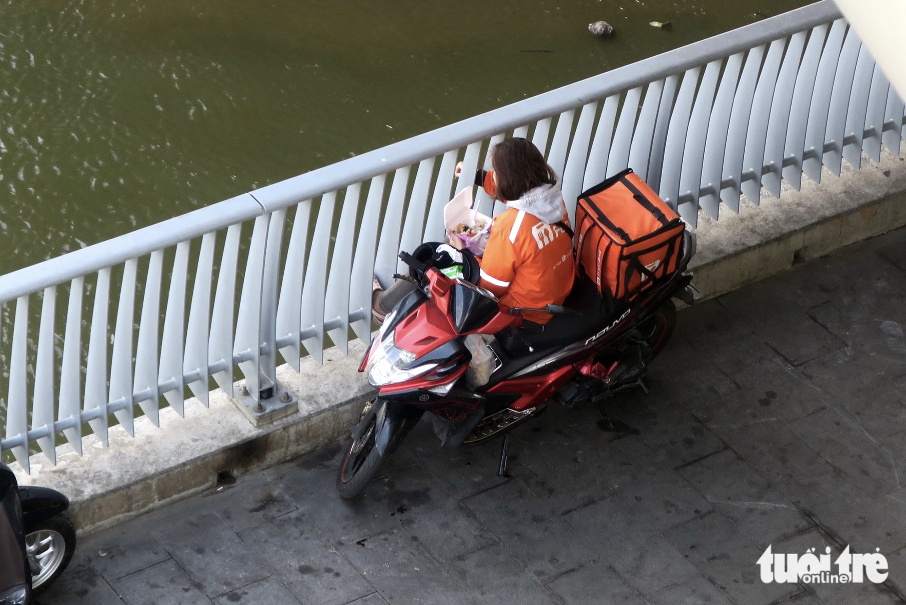 A delivery woman has lunch at the foot of a bridge in Ho Chi Minh City to avoid the sun. Photo: T.T.D. / Tuoi Tre