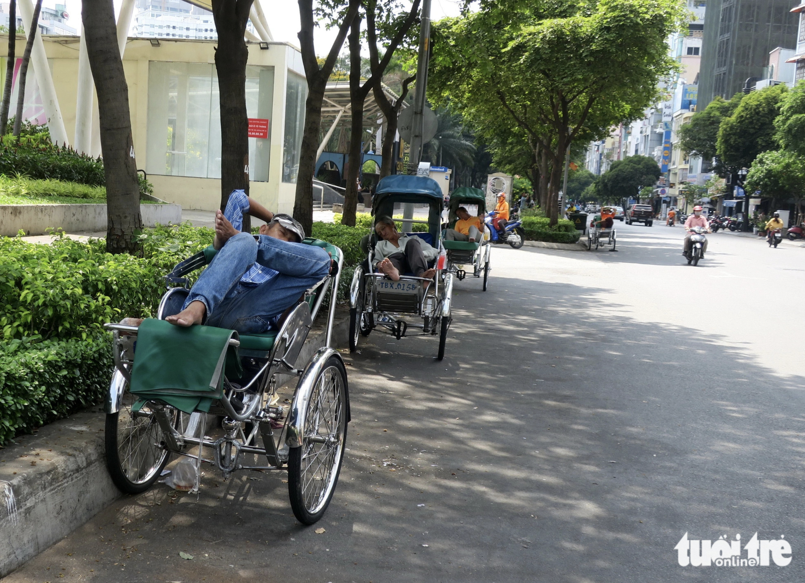 Drivers of  'xich lo,' or pedicabs, take a rest in the shade of trees along Le Lai Street in downtown Ho Chi Minh City. Photo: T.T.D. / Tuoi Tre