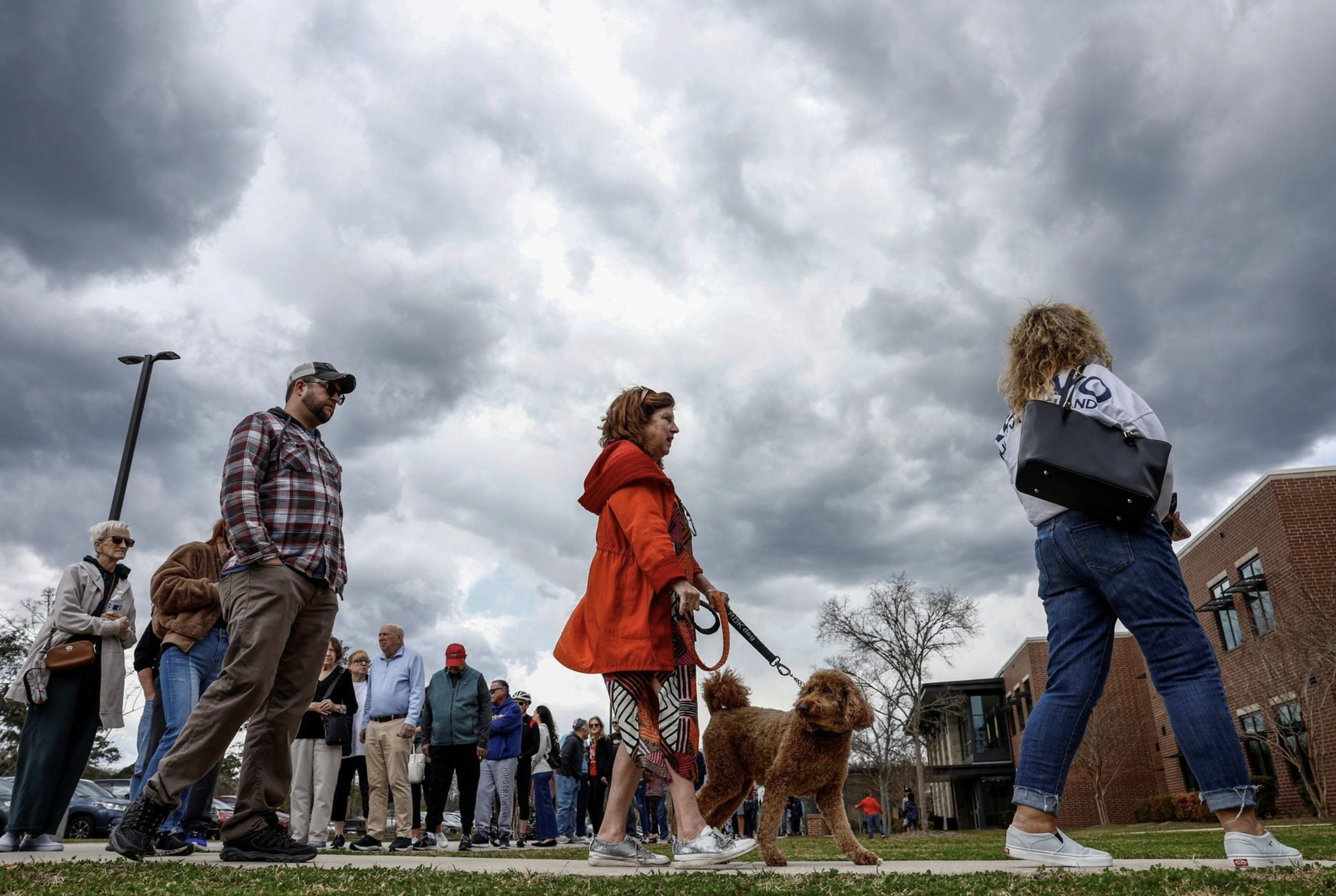 A woman with a dog stands in line to cast her vote in the South Carolina Republican presidential primary election, at the Jennie Moore Elementary School, in Mount Pleasant, South Carolina, U.S., February 24, 2024. Photo: Reuters