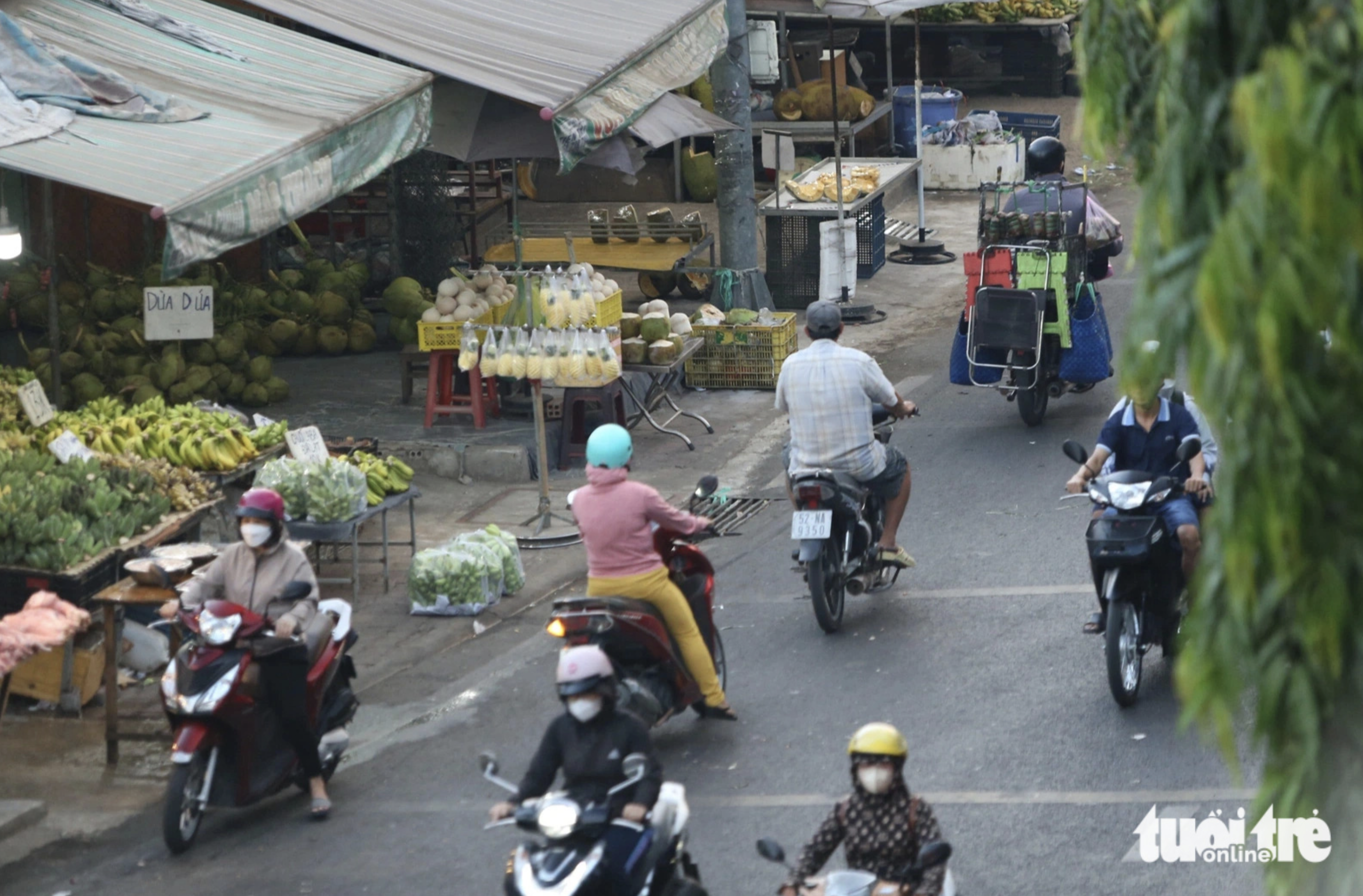 Market-goers ride their motorcycles on the wrong side of National Highway 1 to buy farm produce at street stalls in front of Thu Duc Wholesale Market. Photo: Minh Hoa / Tuoi Tre