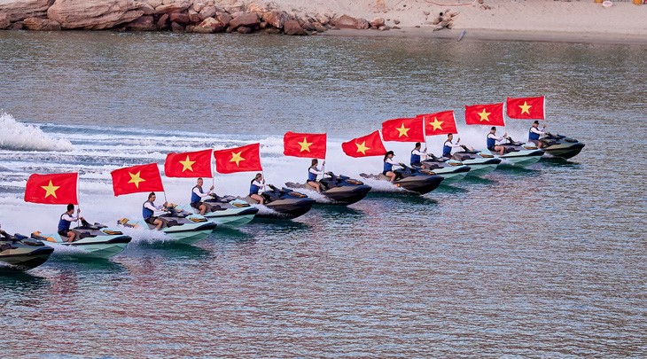 Athletes holding the Vietnamese flag in a jetski performance. Photo: M.H. / Tuoi Tre