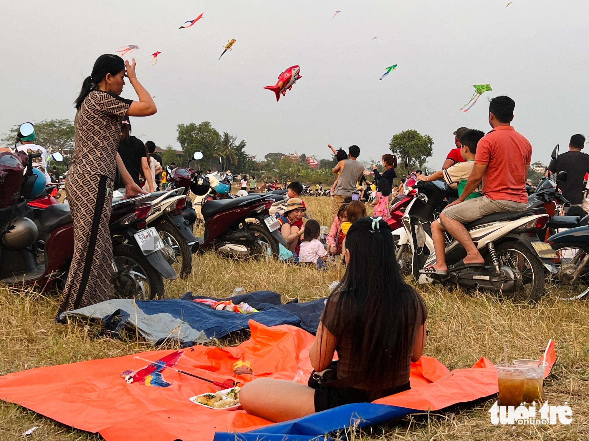 A family relaxes on a tarp and enjoys snacks at a kite-flying field along Nguyen Thi Danh Road in the suburban district of Hoc Mon, Ho Chi Minh City. Photo: Yen Trinh / Tuoi Tre