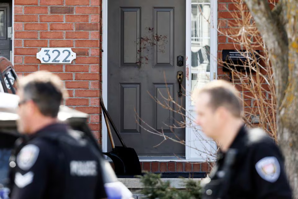 Ottawa Police Service officers walk past a door smeared in blood after four children and two adults were found dead inside a neighbouring house in the Ottawa suburb of Barrhaven, Ontario, Canada March 7, 2024. Photo: Reuters