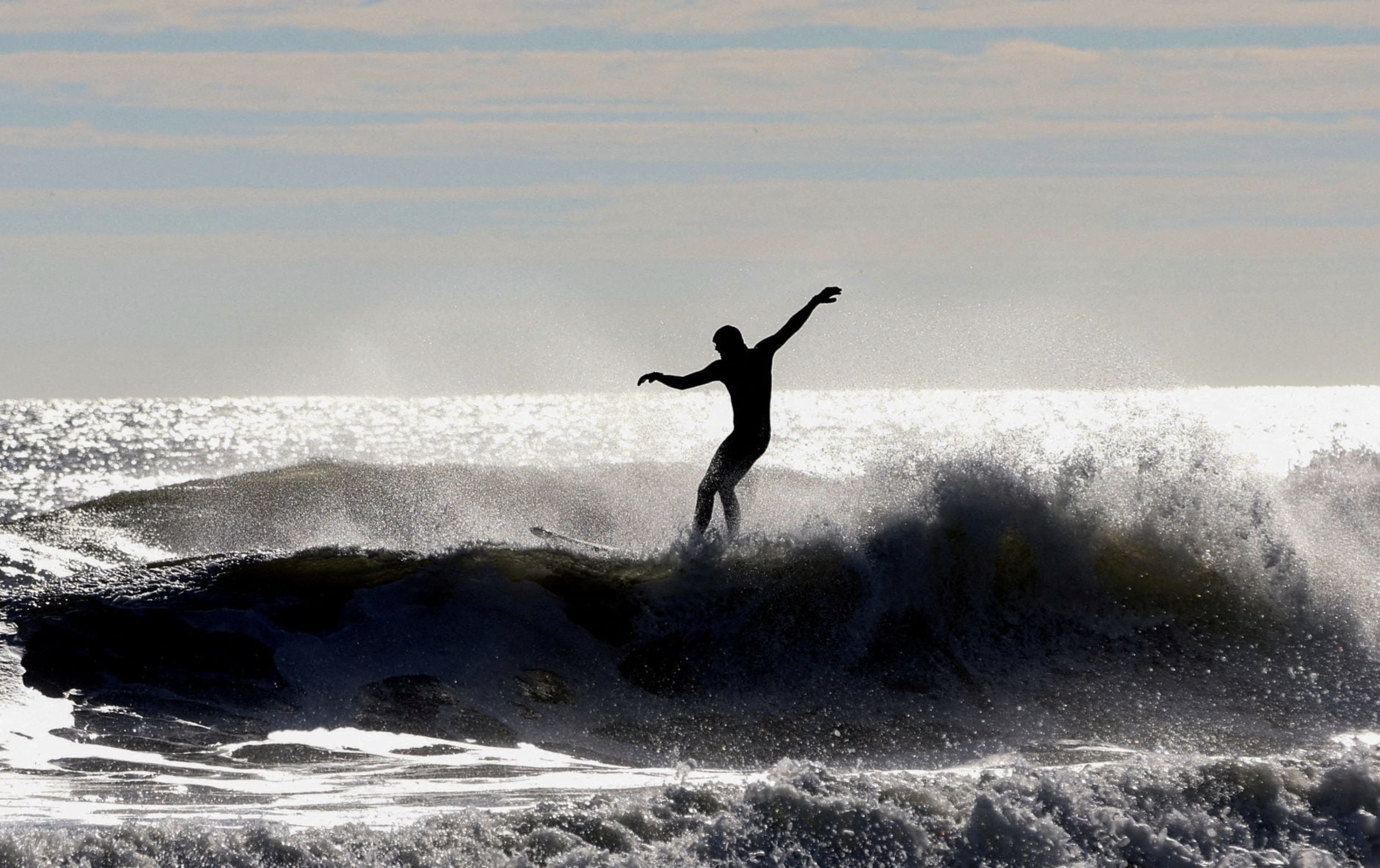 A surfer rides a wave in the Atlantic Ocean off Belmar, New Jersey, U.S., November 27, 2023. Photo: Reuters