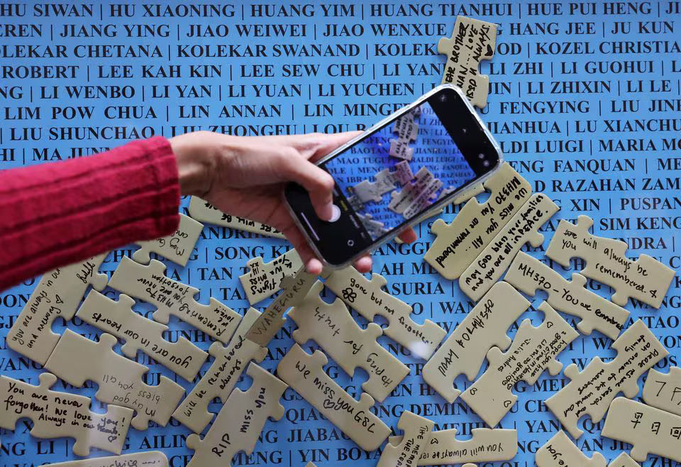 A visitor takes a picture of the well-wishes placed on the names of crew members and passengers of the missing Malaysia Airlines flight MH370, displayed during a remembrance event marking the 10th anniversary of its disappearance, in Subang Jaya, Malaysia March 3, 2024. Photo: Reuters