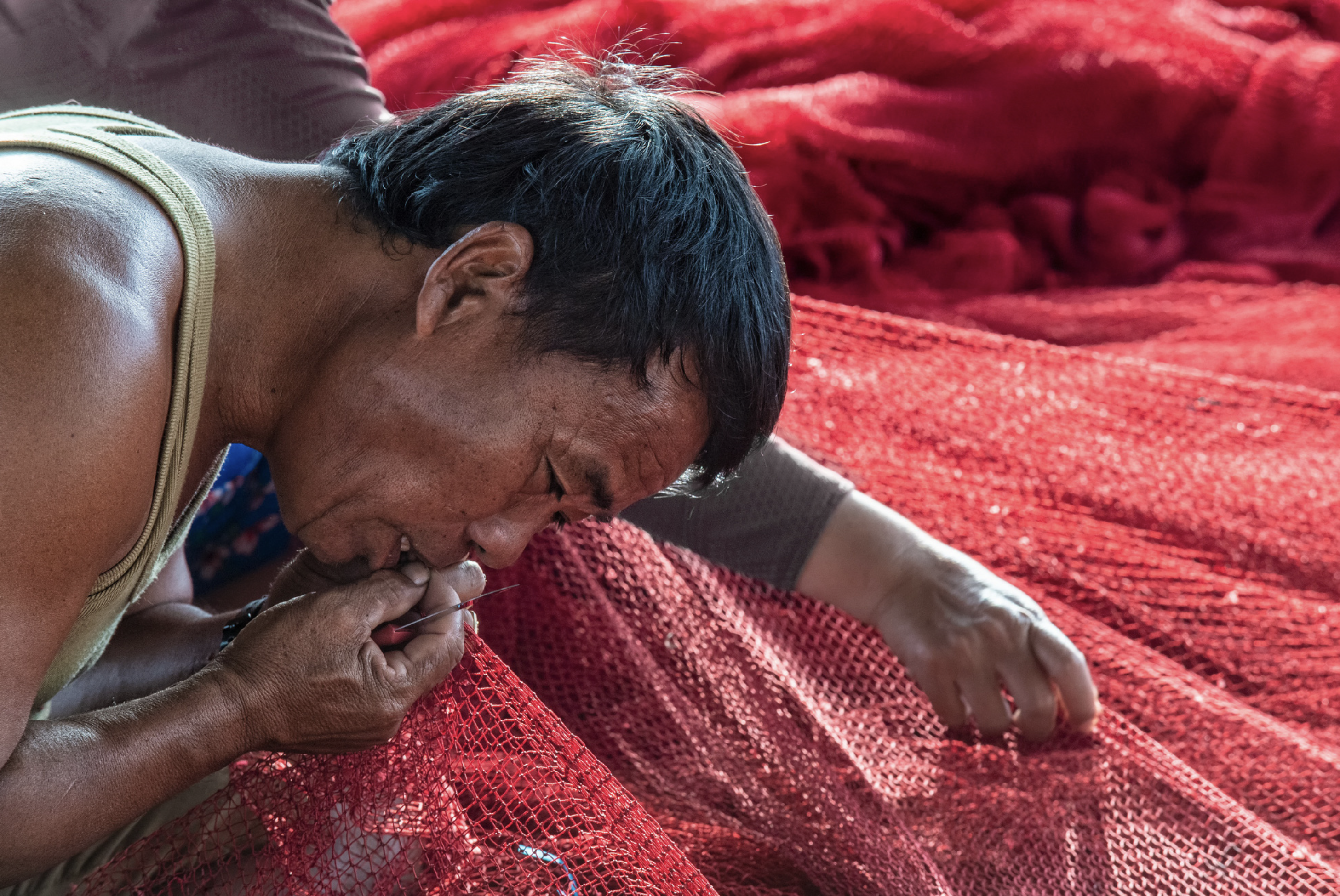 Chin Nghe, owner of a fishing boat, hurriedly fixed his net after he finished a fishing trip. Photo: Ly Hoang Long / Tuoi Tre