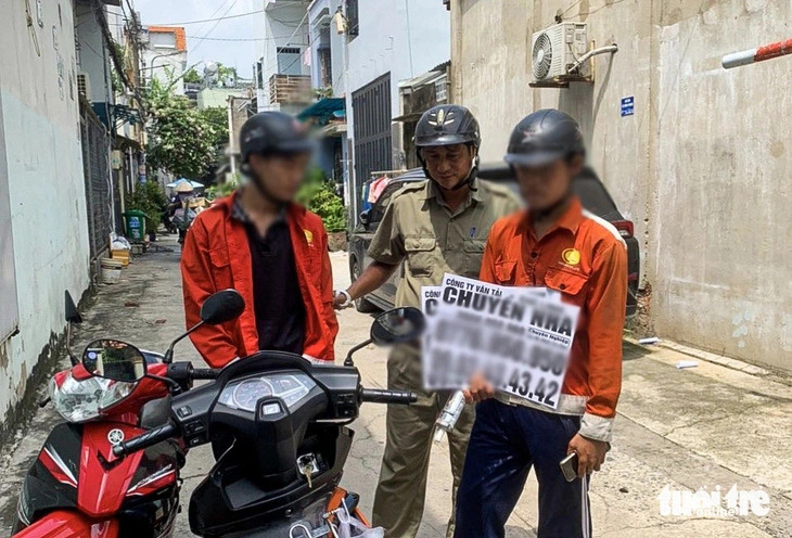 A police officer arrests two individuals in the middle of illegally placing adverts in Thoi An Ward, District 12, Ho Chi Minh City, March 2024. Photo: Giai Thuy / Tuoi Tre