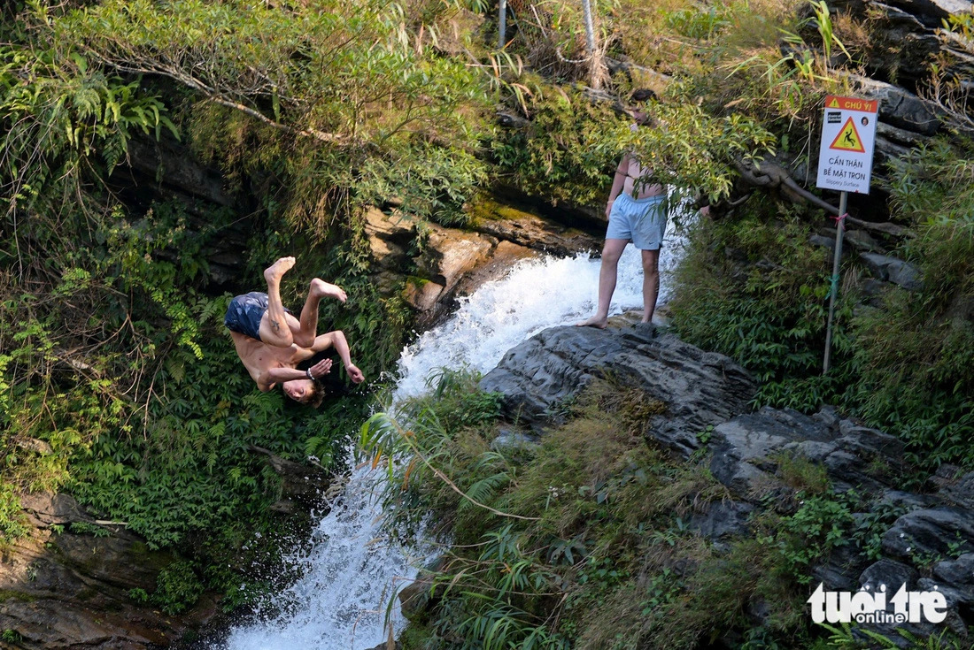 A foreign traveler is seen jumping into the water at the foot of the Du Gia waterfall from a high rock. Photo: Nam Tran / Tuoi Tre