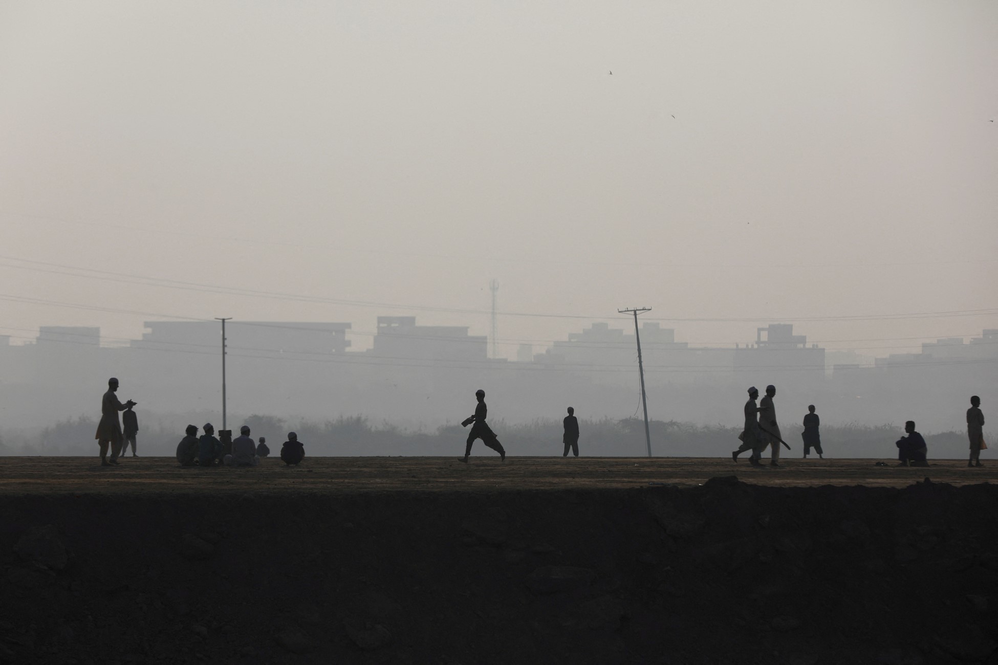 Children are silhouetted as they play cricket amid smog, as air pollution levels rise in Karachi, Pakistan, November 10, 2023. Photo: Reuters