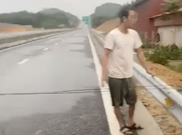 Man stretches rope across expressway that has no drainage ditches in northern Vietnam