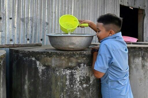 A young boy collects fresh water from a tank in Ben Tre province, where some are now forced to buy water for even domestic needs. Photo: AFP